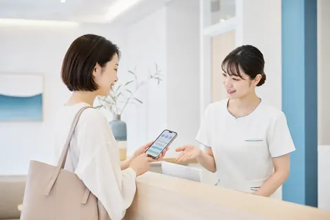 スマートフォンを使った受付方法を案内するスタッフのイメージ